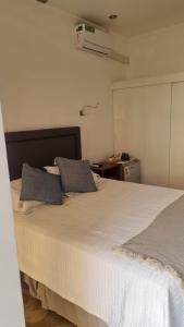 1 dormitorio con 1 cama blanca grande y 2 almohadas en Suites & Habitaciones Acapulco La Lisera, en Arica