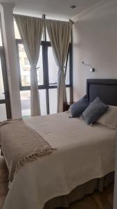 a bedroom with a large bed with a large window at Suites & Habitaciones Acapulco La Lisera in Arica