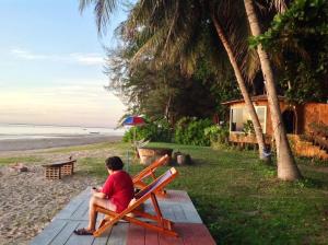 una persona sentada en un banco en la playa en Ban Tawansongfa en Lang Suan