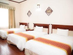 une chambre d'hôtel avec trois lits dans une chambre dans l'établissement Sport Hotel HN - by BAY LUXURY, à Hanoï