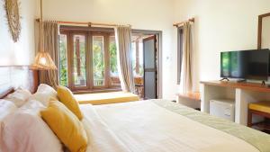 1 dormitorio con 1 cama blanca y TV en Treeya Lanta en Ko Lanta