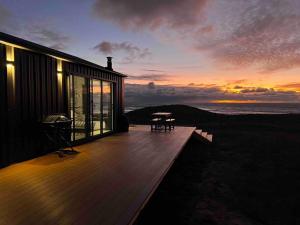 ein Haus mit einer Terrasse mit einem Sonnenuntergang im Hintergrund in der Unterkunft Red Rock Hut, King Island 