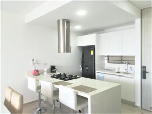 a kitchen with a white counter and a black refrigerator at Apartamento Cautivador SAMARIA CLUB DE PLAYA con Salida Directa Al Mar y Sus Hermosas Playas de Pozos Colorados Santa Marta in Santa Marta