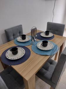 a wooden table with three cups and plates on it at Hermoso Apartamento en zona exclusiva in Armenia