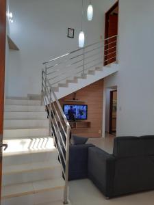 ein Wohnzimmer mit einer Treppe und einem TV in der Unterkunft Sobrado com Suíte Master em Capitólio Furnas MG in São José da Barra