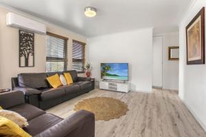 ein Wohnzimmer mit Sofa und Fernseher in der Unterkunft Rosalie Unit 1, 4 Margaret St, Kings Beach in Caloundra