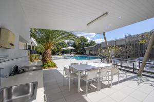 un patio al aire libre con mesa y sillas y una piscina en Boulevard North Lakes, en North Lakes