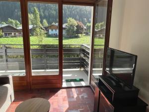 un salon avec une grande porte en verre et une télévision dans l'établissement Résidence Bois du Bouchet, appartement vue montagne, calme, parking gratuit, proche centre, à Chamonix-Mont-Blanc