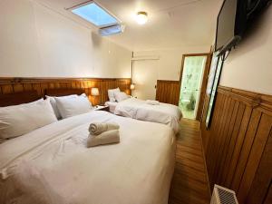 two beds in a hotel room with a window at Hostal Cordillera in Punta Arenas