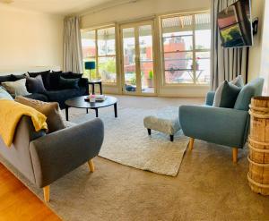 ein Wohnzimmer mit einem Sofa, Stühlen und einem Tisch in der Unterkunft Luxury Inner City Townhouse in Bendigo