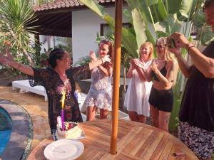 un grupo de mujeres de pie alrededor de una mesa con un pastel en Banana Leaf Resort, en Gili Trawangan