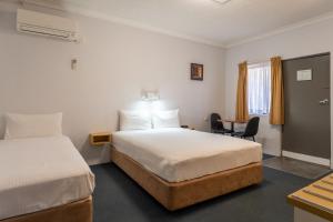 una camera d'albergo con 2 letti e una scrivania di Port Aloha Motel a Port Macquarie