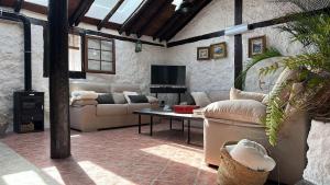 sala de estar con sofás, mesa y TV en CASA MARA Casa Rural con terraza, barbacoa y vistas al Teide, en Tanque