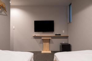 大阪市にある3U NAMBA MINAMI by DOYANENのベッド2台と壁掛けテレビが備わる客室です。