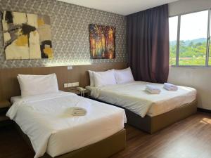 um quarto de hotel com duas camas e uma janela em Hotel DarulMakmur Jerantut em Jerantut