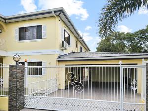 RambertThe Green Palms Getaway, Palmiste, San Fernando - 6 BR 4 Bath 12 guests的白色围栏的黄色房子