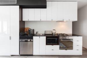 een keuken met witte kasten en roestvrijstalen apparatuur bij Experience the Buzzing Swanston Locale from QV in Melbourne
