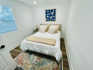 a white bedroom with a bed and a rug at Modern Gem 2 miles from Sofi in Los Angeles