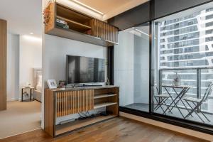een woonkamer met een tv en een glazen wand bij Flagstaff Chic - A Refreshing Balcony Retreat in Melbourne