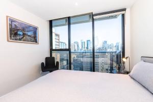 ein Schlafzimmer mit einem weißen Bett und einem großen Fenster in der Unterkunft Elevated Elegance in the City's Chic Paris End in Melbourne