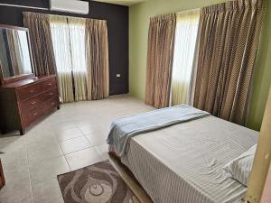 a bedroom with a bed and a dresser and windows at The Green Palms Getaway, Palmiste, San Fernando - 6 BR 4 Bath 12 guests 