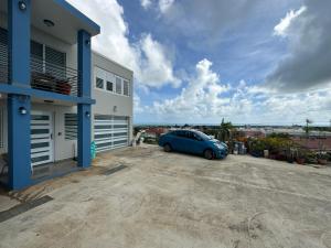 una macchina blu parcheggiata di fronte a un edificio di Black Pearl a Guayama