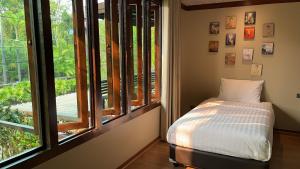 1 dormitorio con 1 cama frente a una ventana en Seed Villa·Nimman Thai Local Lanna garden villa, en Chiang Mai