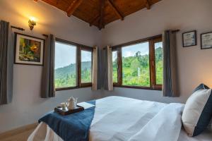 - une chambre avec un lit et des fenêtres offrant une vue dans l'établissement SaffronStays The Clairmont Cottage,Mukteshwar, à Mukteswar