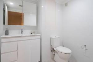 a white bathroom with a toilet and a sink at 'Zen Boutique' A Well-connected Studio with Parking in Sydney