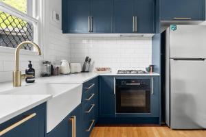 a kitchen with blue cabinets and a white refrigerator at Pocket of Petersham - A Stylish Inner-West Retreat in Sydney