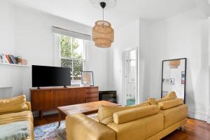 a living room with a couch and a tv at Pocket of Petersham - A Stylish Inner-West Retreat in Sydney