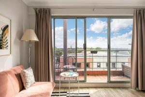 salon z kanapą i dużym oknem w obiekcie 'Georgina' Mid-Century Modern Poolside Stay w mieście Sydney