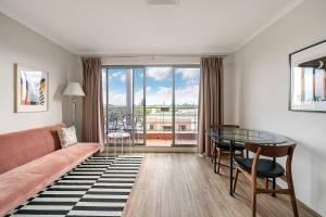 a living room with a couch and a glass table at 'Georgina' Mid-Century Modern Poolside Stay in Sydney