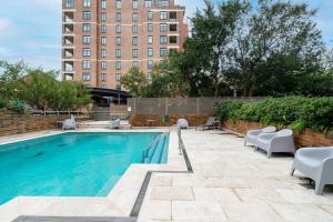 a swimming pool with chairs and a building in the background at 'Georgina' Mid-Century Modern Poolside Stay in Sydney