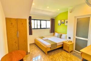 een slaapkamer met een bed met groene muren bij Sunrise Valley Dalat Hotel in Da Lat
