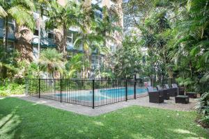 a fence with chairs and a pool in front of a building at Central and Secluded - Potts Point Paradise with Pool in Sydney
