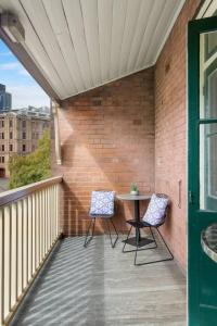 悉尼Eclectic Heritage Comfort with Terrace and Views的砖墙阳台配有两把椅子和一张桌子