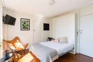 1 dormitorio con 1 cama y 1 silla en Leafy Paddington Studio with Harbour Views en Sídney