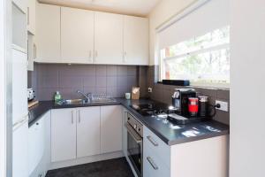 una cocina con armarios blancos y fregadero en Leafy Paddington Studio with Harbour Views en Sídney