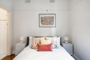 een slaapkamer met een bed met witte lakens en kussens bij Coogee Classic - Coastal Gem Close to Beach in Sydney