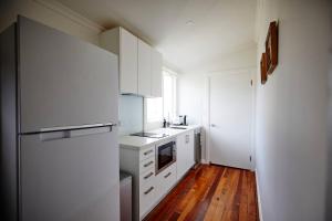 een keuken met witte apparatuur en een houten vloer bij Easy Esperanza - Compact Indoor-outdoor Living in Sydney