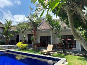 a villa with a pool in front of a house at Pererenan nengah guest house in Canggu