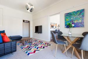 uma sala de estar com uma mesa e cadeiras e uma televisão em Harbourfront Art Deco Hall - Sought-after in Sydney em Sydney