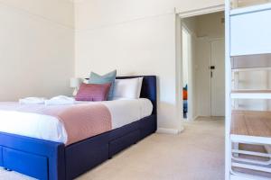 a bedroom with a large bed with a blue frame at Harbourfront Art Deco Hall - Sought-after in Sydney in Sydney