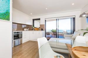cocina y sala de estar con mesa de cristal en Bondi Beachfront Lifestyle - Ocean Views and Parking en Sídney