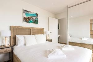 Habitación blanca con 2 camas y espejo. en Bondi Beachfront Lifestyle - Ocean Views and Parking en Sídney