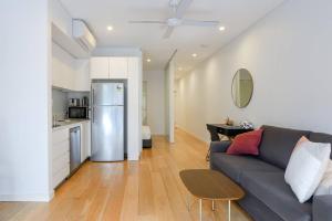 a living room with a couch and a kitchen at Lush Modern Sanctuary in the Heart of Surry Hills in Sydney