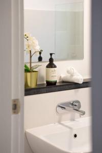 Un baño blanco con lavabo y espejo. en Harbourfront meets Heritage Chic near Barangaroo, en Sídney 18 fotos más