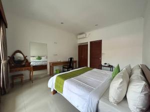 a bedroom with a bed and a desk and a mirror at Pererenan nengah guest house in Canggu
