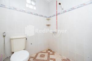 a bathroom with a toilet and a shower at Dukuh Kupang Residence Mitra RedDoorz in Surabaya